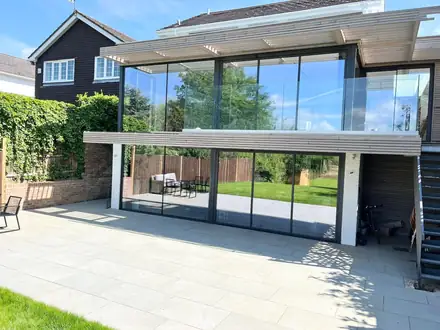 Pale porcelain patio behind a glass-fronted extension