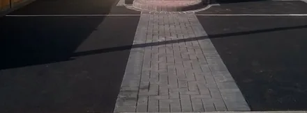 Black tarmac drive split by a grey block-paved path